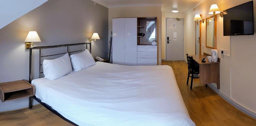 a bedroom with a large white bed and a desk at 247Hotel.com in Oldham