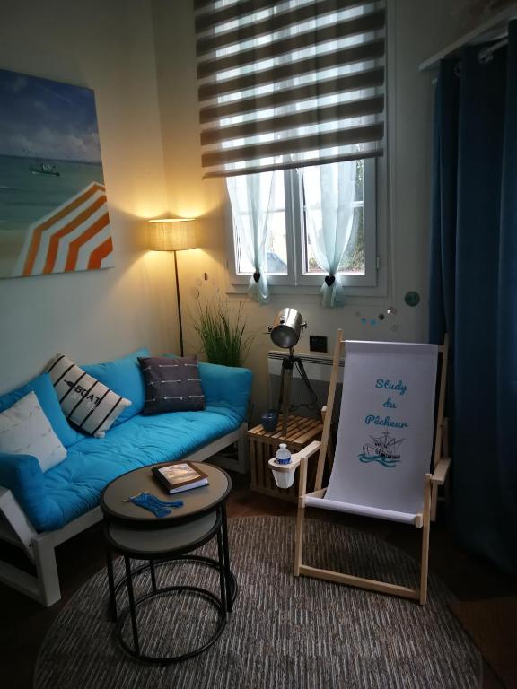 a living room with a blue couch and a painting at Study du pêcheur in Trouville-sur-Mer