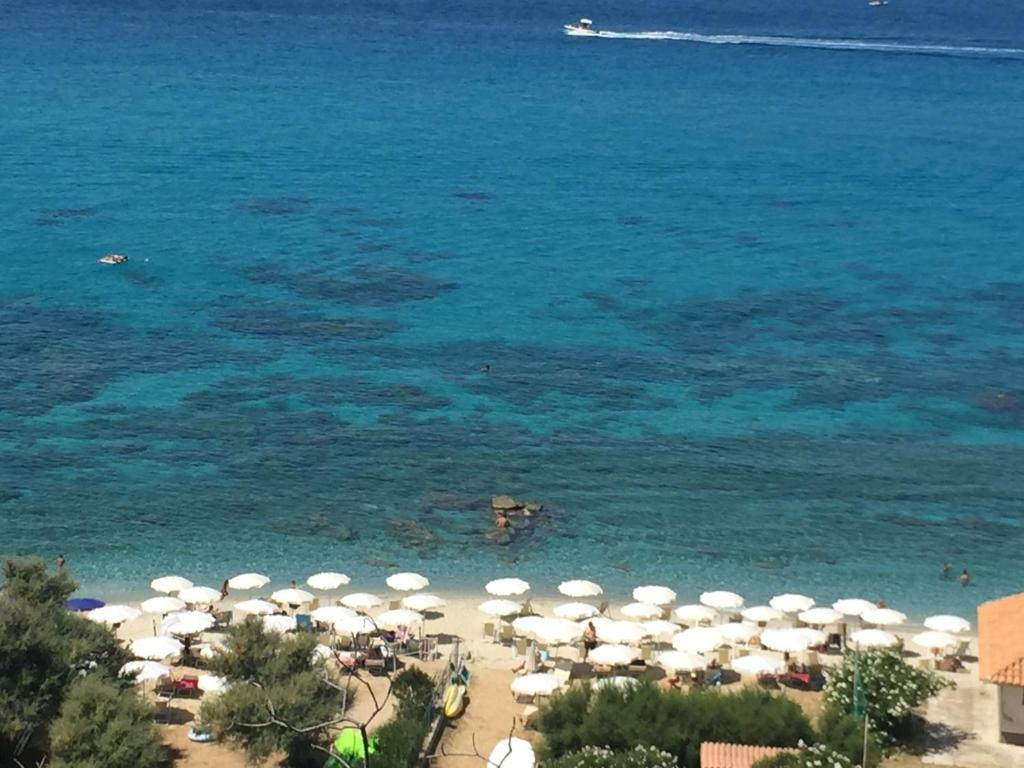 a beach with umbrellas and people in the water at Residenza Gherly in Capo Vaticano