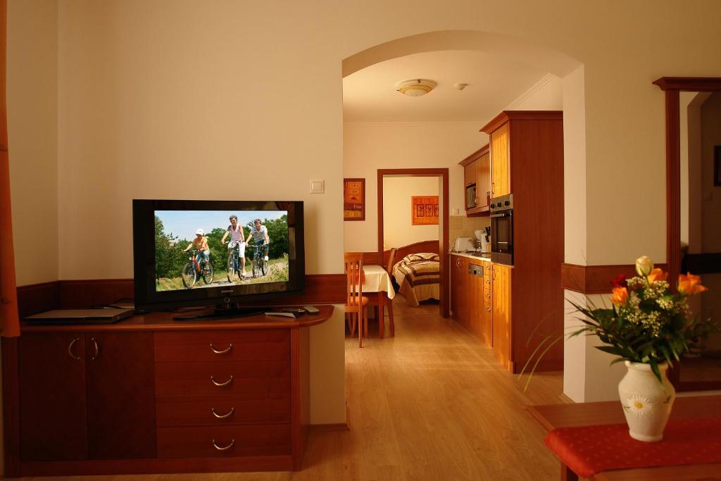 a living room with a television on a dresser at Szerencsemák Panzió in Kehidakustány