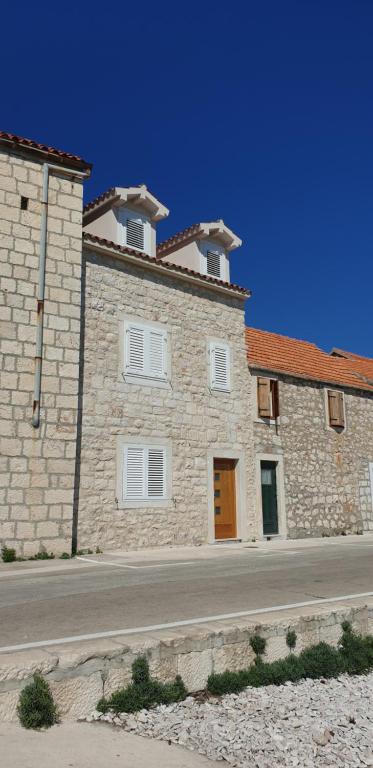 a large stone building with white windows on a street at Studio apartman Megy in Sutivan