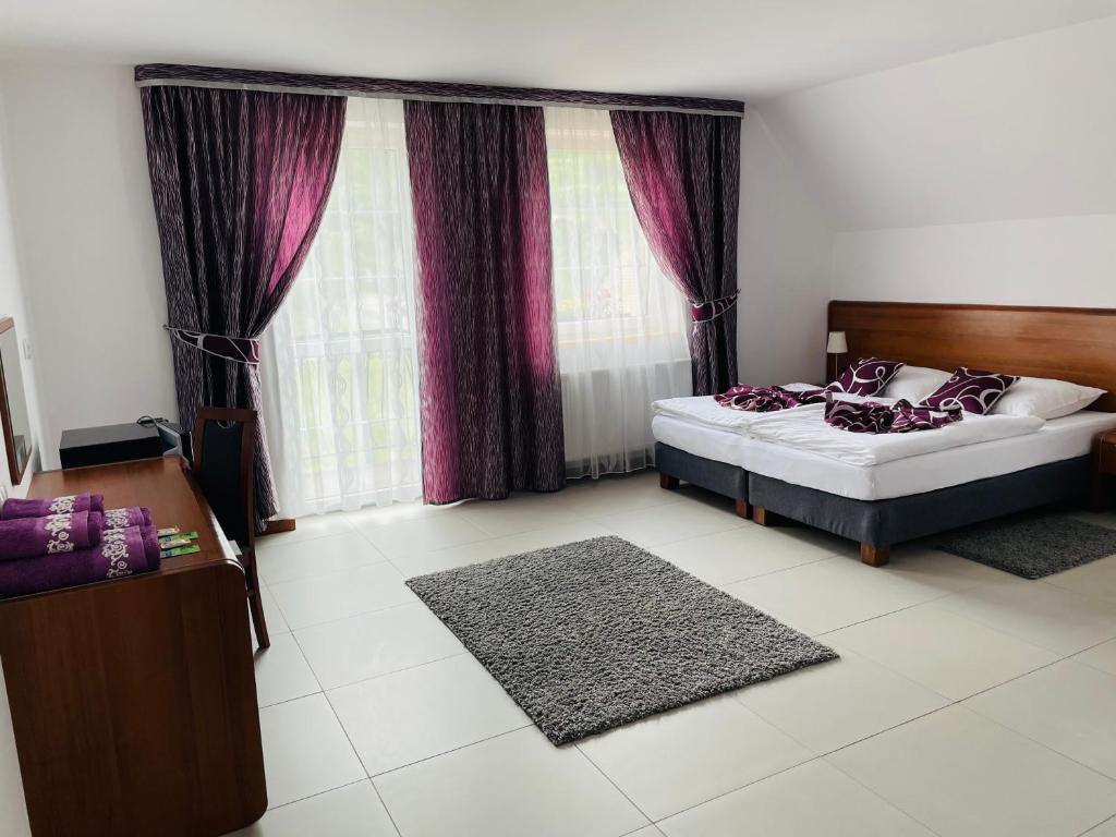 sypialnia z łóżkiem i oknem z fioletowymi zasłonami w obiekcie Pod Orłem w Kudowie Zdroju