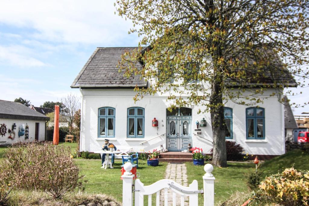 a white house with a woman sitting in front of it at Moby Dick im Haus Käpt'n Andresen in Westerland