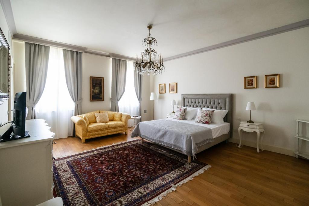 sypialnia z łóżkiem, kanapą i żyrandolem w obiekcie Villa San Pietro w mieście Desenzano del Garda