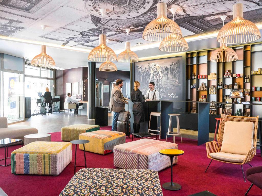 a lobby of a hotel with people standing at a bar at Novotel Lille Centre Gares in Lille