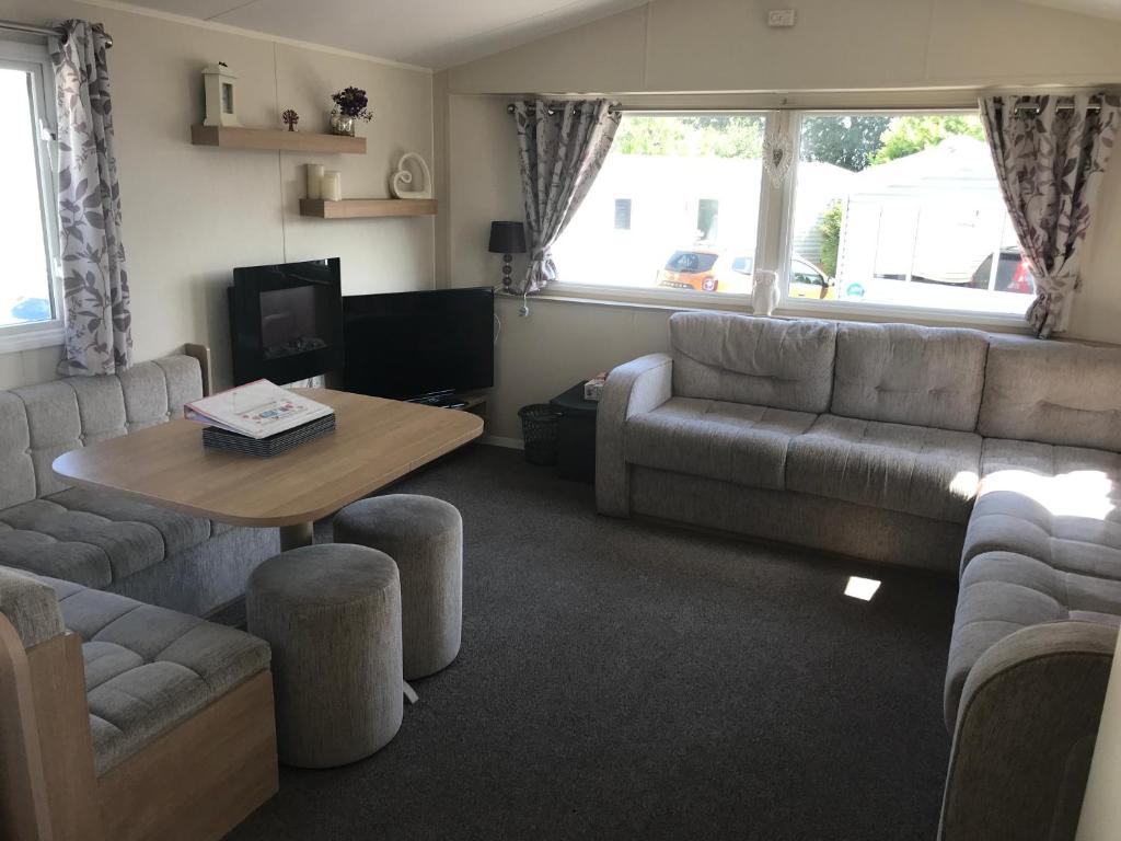 a living room with a couch and a table at Stunning deluxe 3 bedroomed caravan with CH, DG and decking. in Blackpool