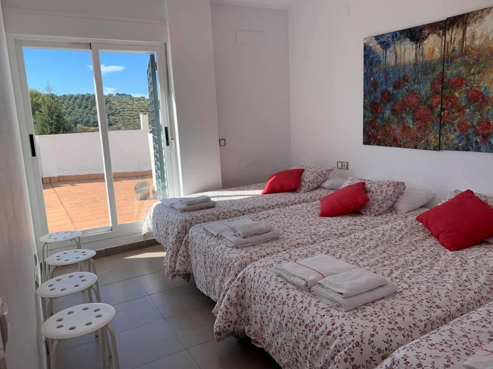 1 dormitorio con 2 camas con almohadas rojas y ventana en Casa Rural Nacimiento del Huéznar - Tomillo 17, en San Nicolás del Puerto