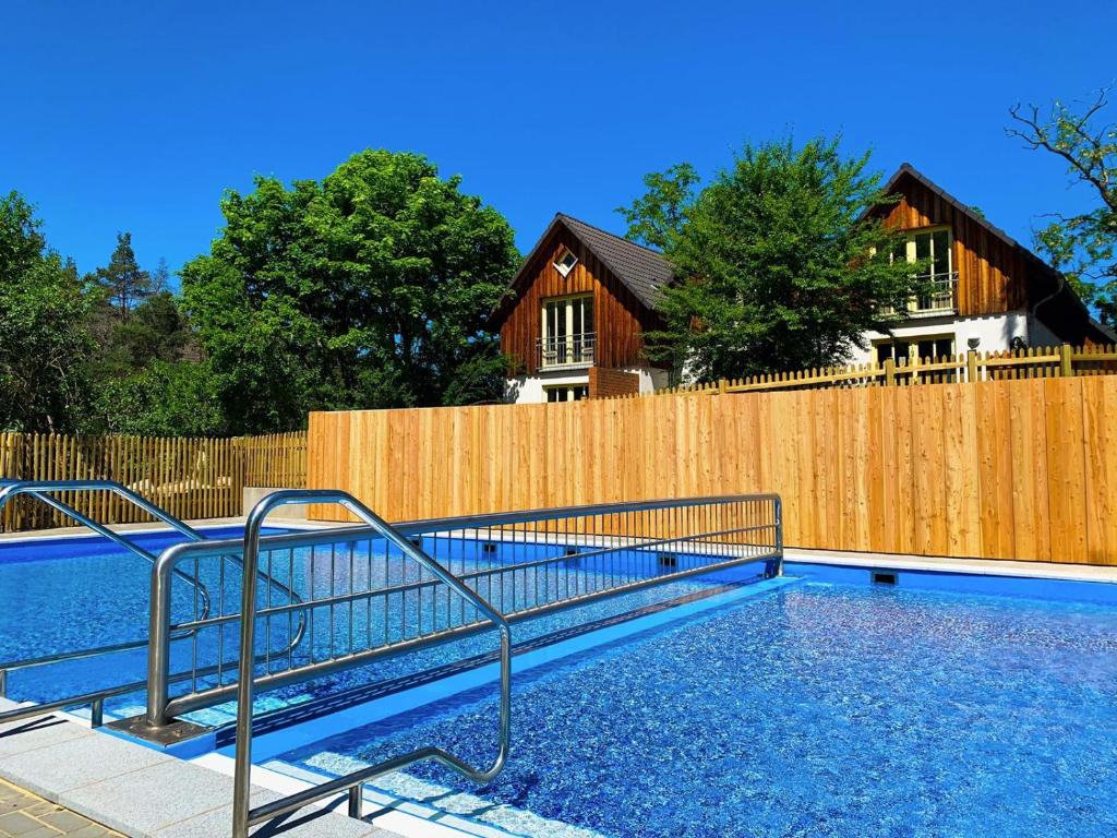 a swimming pool in front of a wooden fence at Family Club Harz in Quedlinburg