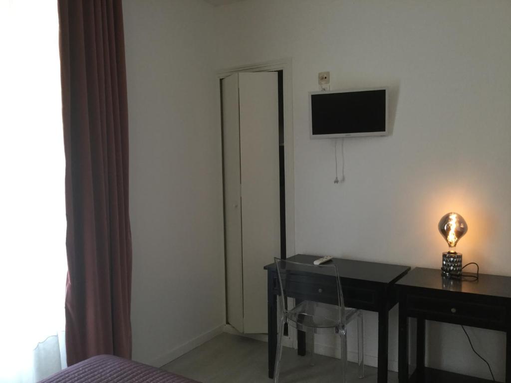 a bedroom with a desk and a television on the wall at Les Pastels in La Roche-sur-Yon