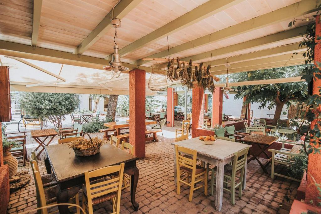 a patio with tables and chairs and a dining area at Saronis Hotel Agistri - Adults Only in Skala