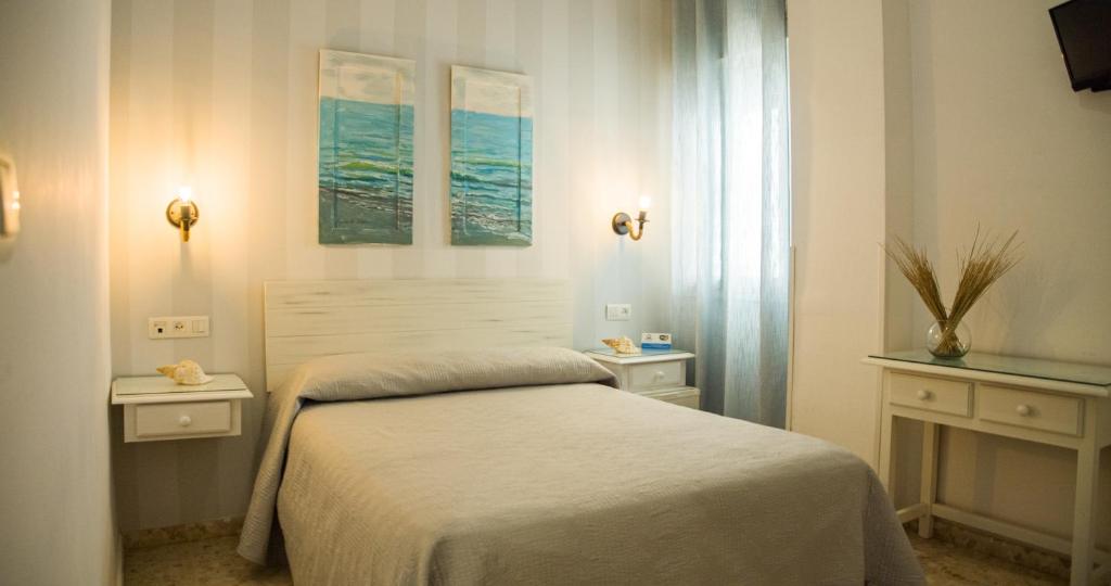 1 dormitorio con 1 cama, 2 mesas y una ventana en Hostal Patio Andaluz en Punta Umbría