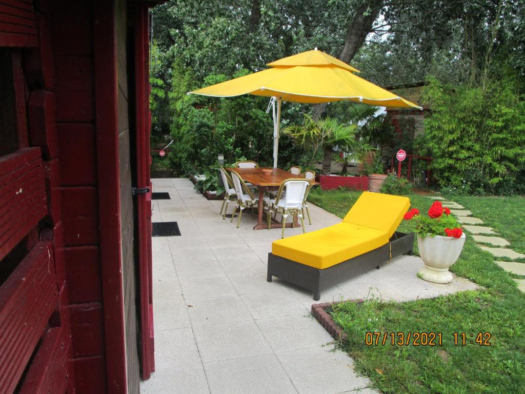 a patio with a table and a yellow umbrella at Locatlantique in Aytré