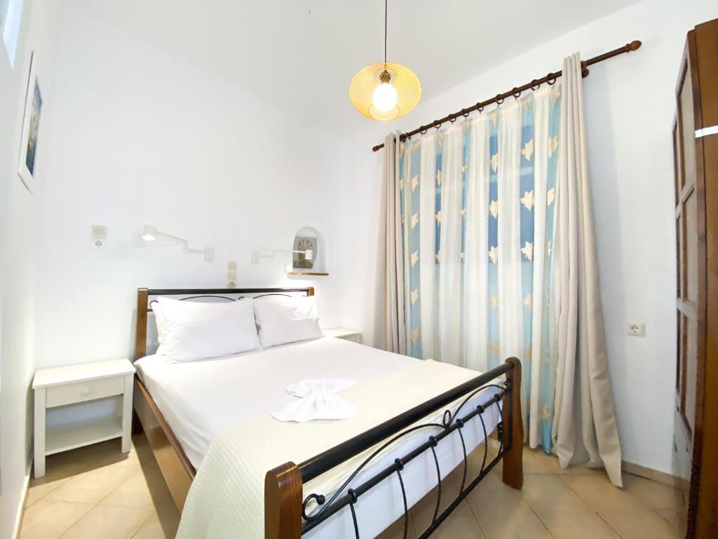 um quarto com uma cama com lençóis brancos e uma janela em Dina Naxos Studios em Agios Prokopios