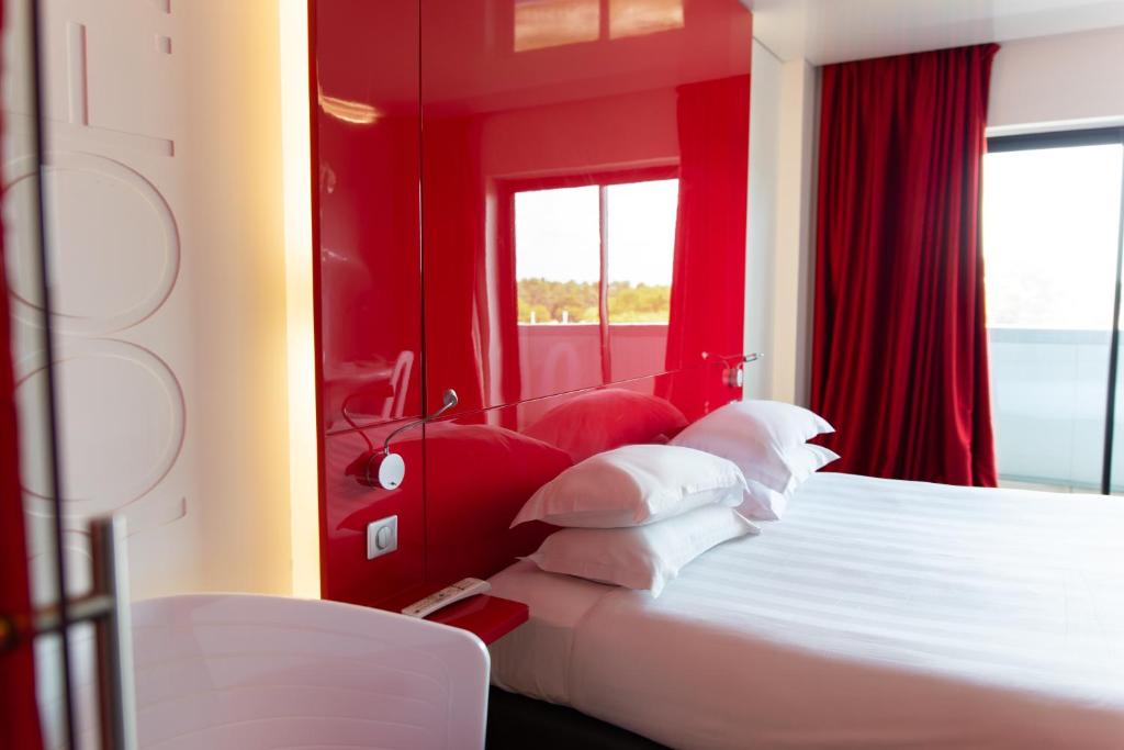a bedroom with red walls and a bed with white pillows at Zenitude Hôtel Résidences Bassin d'Arcachon in La Teste-de-Buch