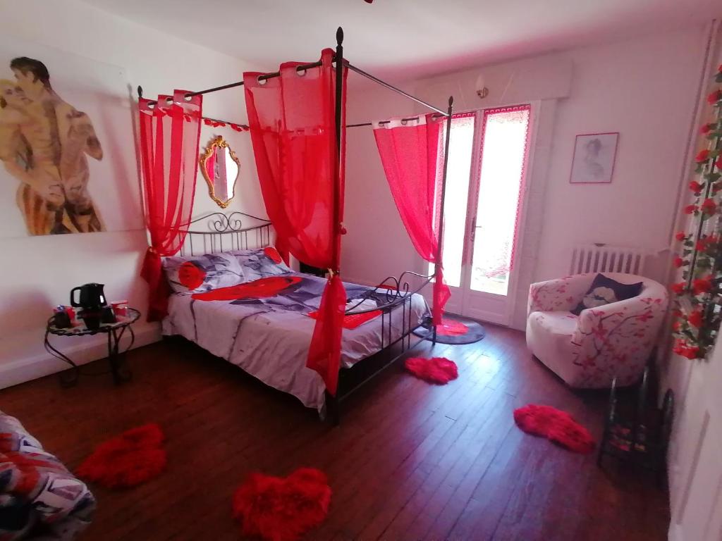 a bedroom with red curtains and a bed and a chair at chambres d hôtes Le labyrinthe du peintre in Bransat
