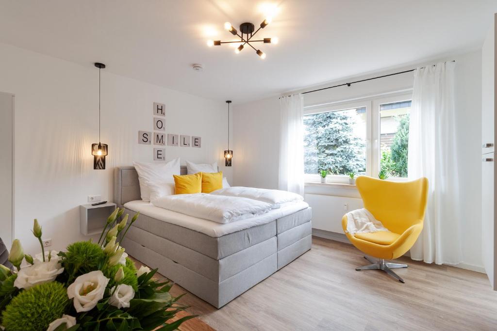 a bedroom with a bed and a yellow chair at Modernes Apartment *Liobablick Nr. 4* - FeWo in Fulda/Petersberg in Petersberg