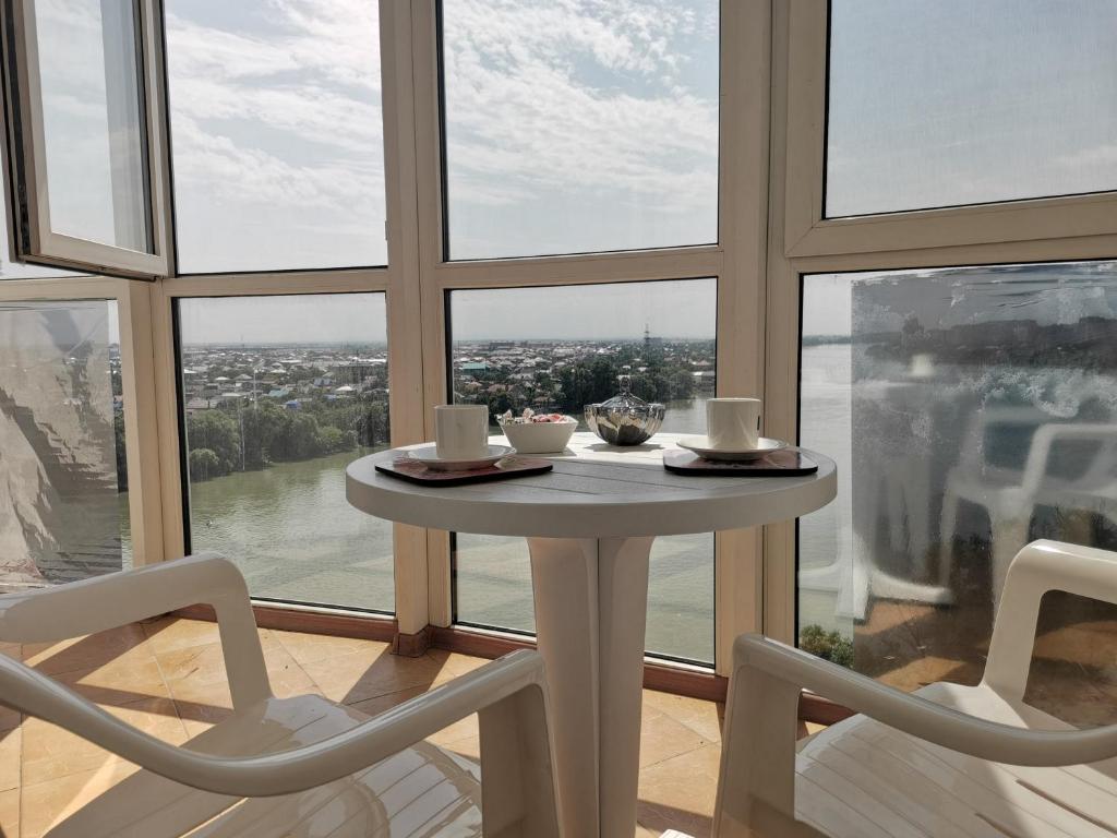 mesa y sillas en una habitación con ventana grande en Квартиры на берегу реки - ЖК Европейский en Krasnodar