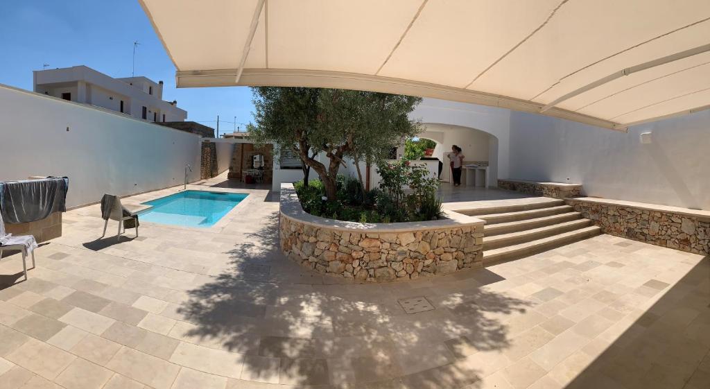 ein Haus mit einem Pool und einem Baum im Innenhof in der Unterkunft Le Liame Antico Trullo in Gagliano del Capo