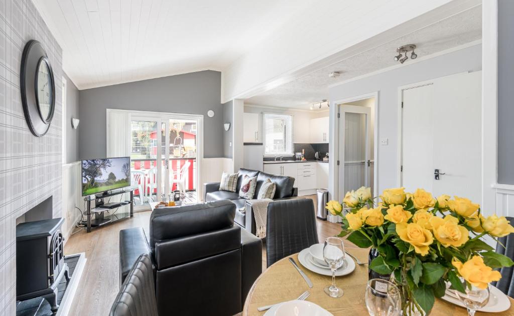 a living room with a table with yellow flowers on it at High Range Self-Catering Chalets in Aviemore