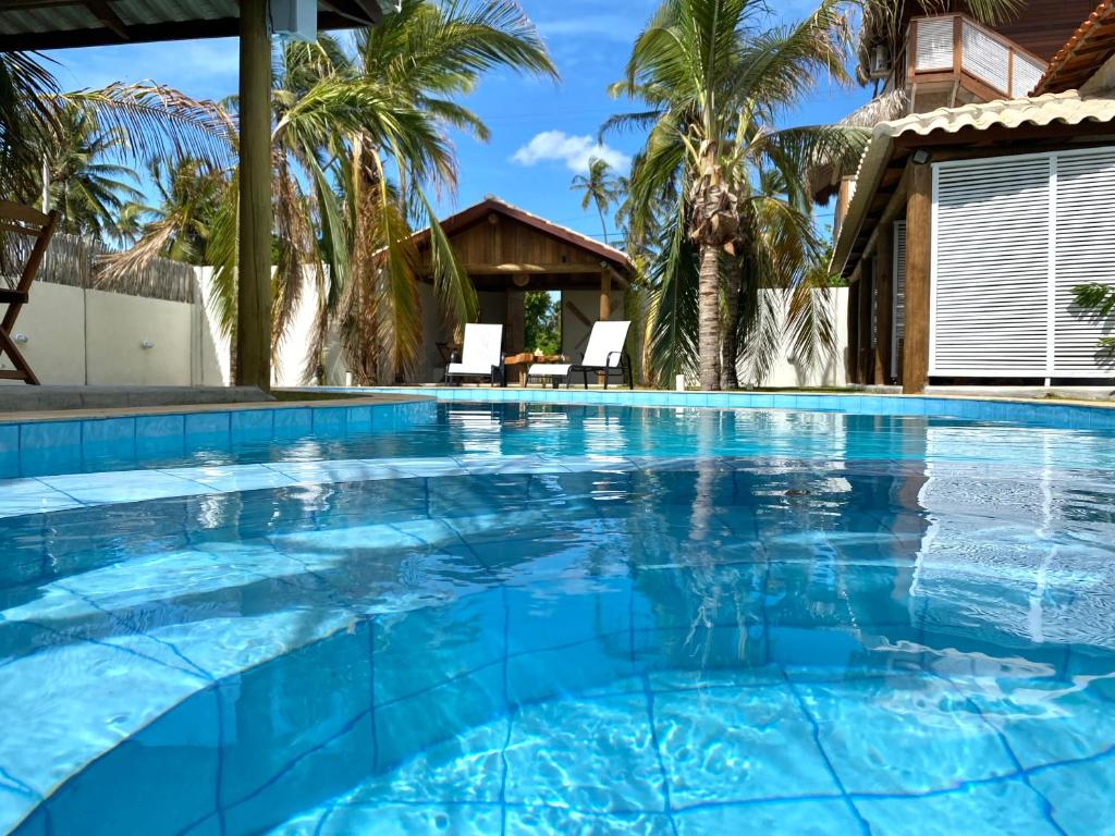 a large blue swimming pool with palm trees in the background at Uba Village in Icaraí