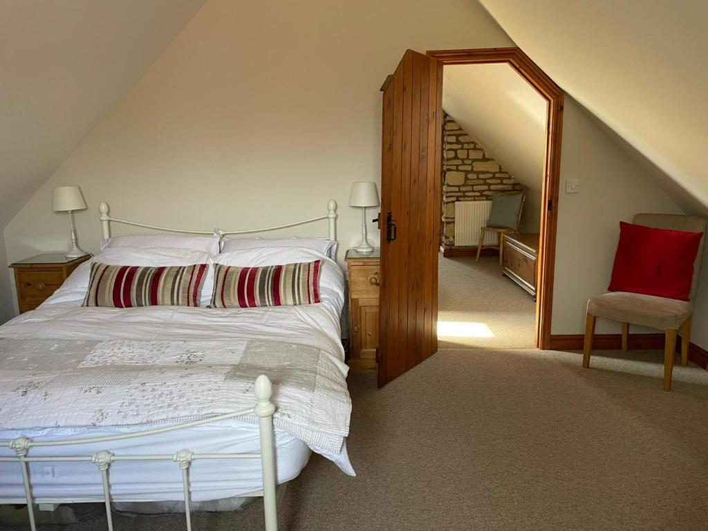a bedroom with a white bed and a red chair at Farriers Cottage in Grantham