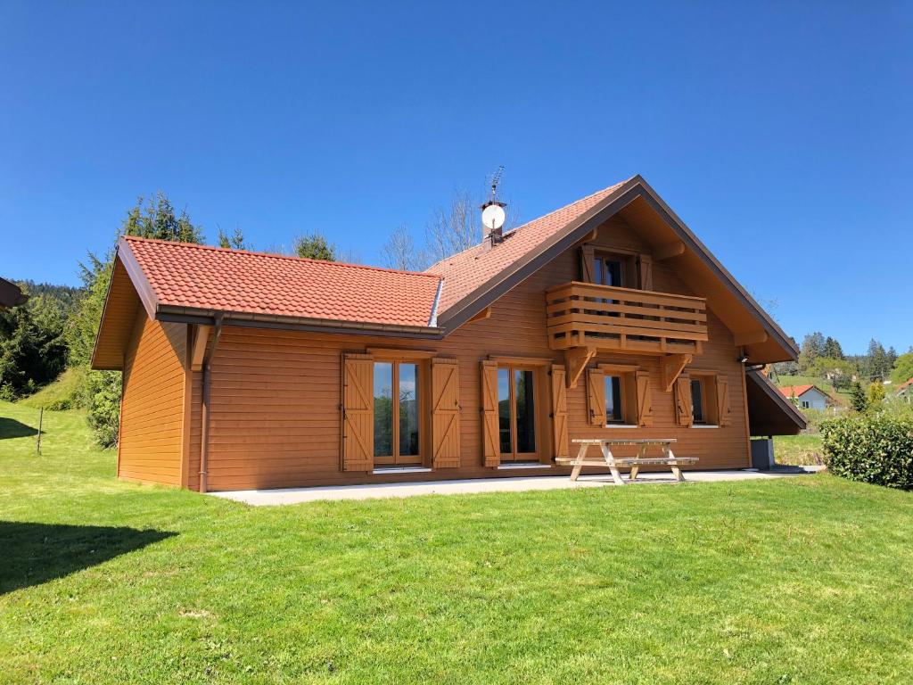 een klein houten huis met een picknicktafel ervoor bij Chalet Gentiane in Gérardmer