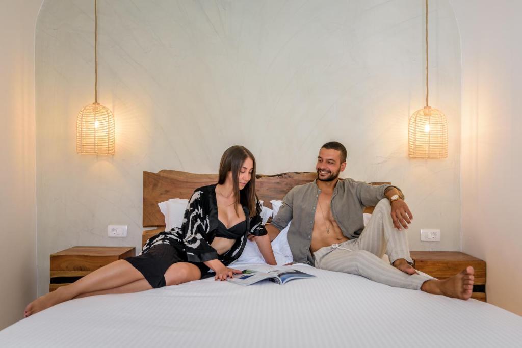 a man and a woman sitting on a bed at Anila Suites in Fira
