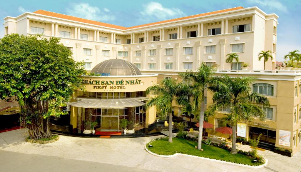 a hotel building with palm trees in front of it at First Hotel in Ho Chi Minh City