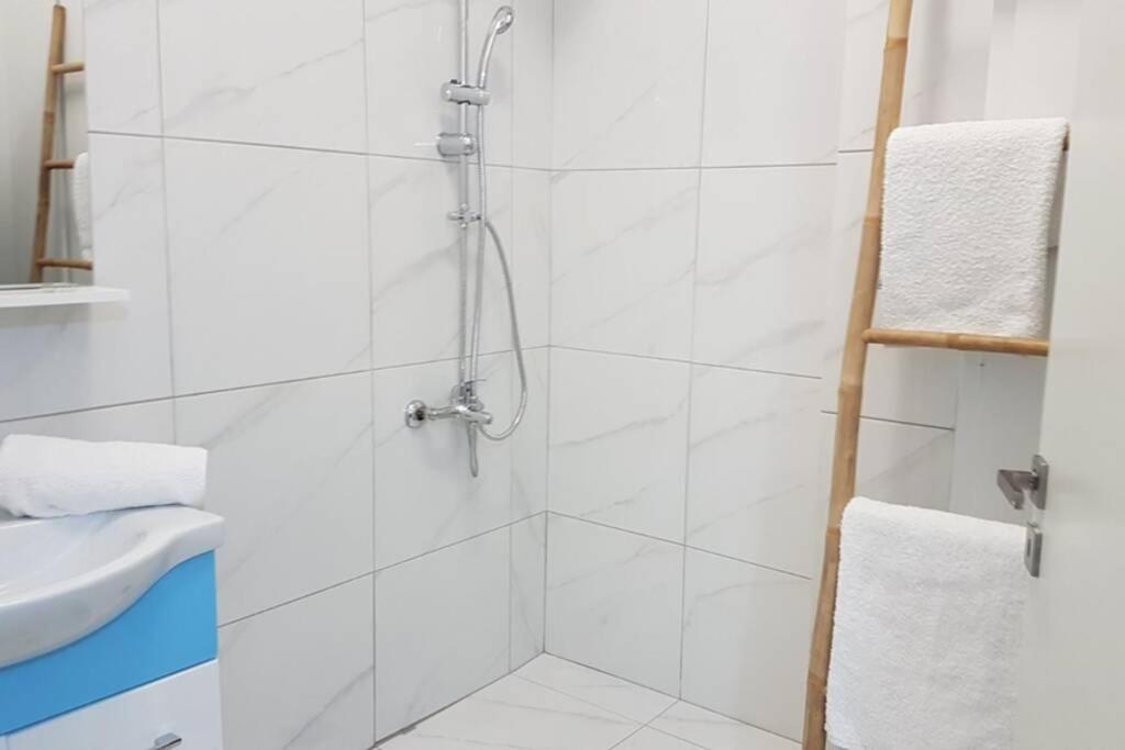Łazienka z prysznicem wyłożona jest białymi kafelkami. w obiekcie Double Apartment - Athens Center, 7 BD, 3 BATH w Atenach
