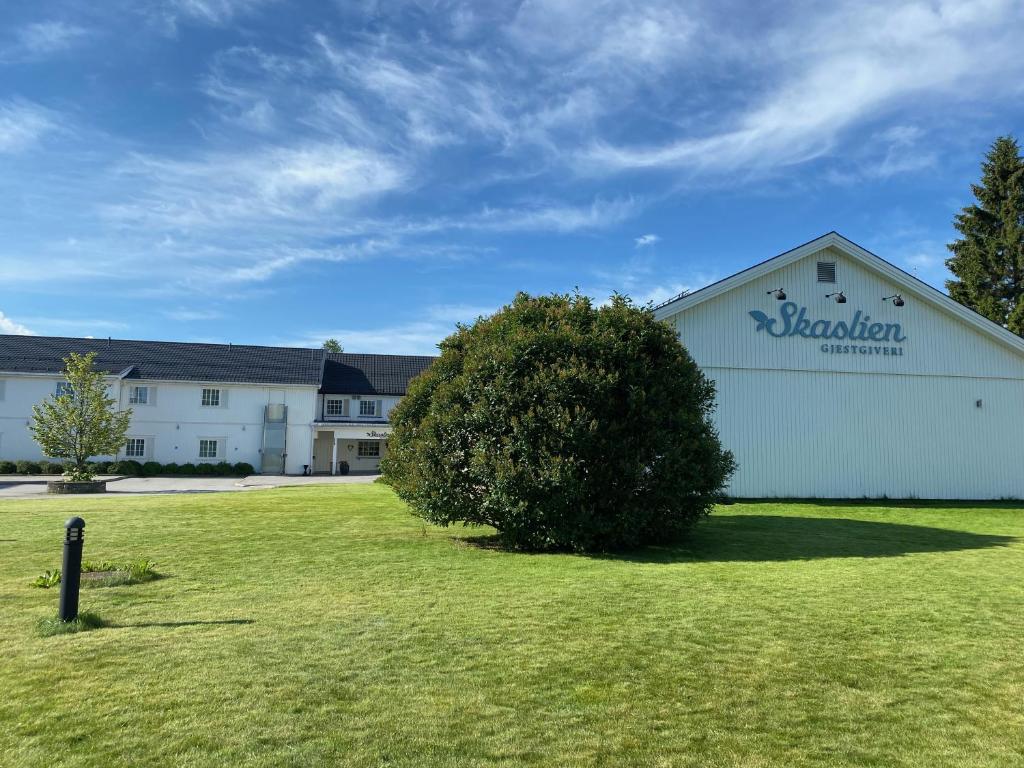 a large white building with a bush in the yard at Skaslien Hotel & Guesthouse in Kirkenær