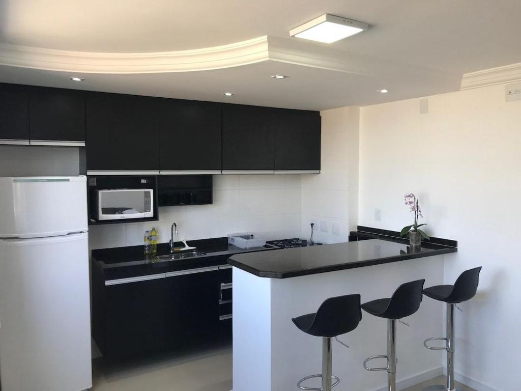 a kitchen with black and white appliances and stools at 703 · Apto inteiro Morumbi 703 ( 5 min-Hosp Einstein) in Sao Paulo