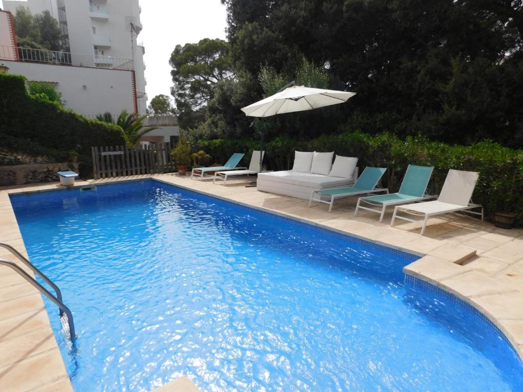 a swimming pool with lounge chairs and an umbrella at Apart.Can Pons,con piscina, a 50 de la playa in Cala Galdana