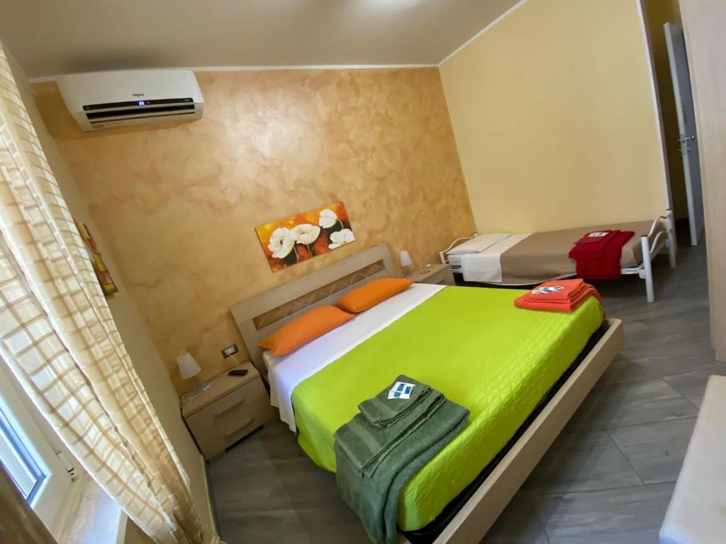 ガリポリにあるB&B Caviraniのベッドルーム1室(緑のシーツとオレンジの枕が備わるベッド1台付)