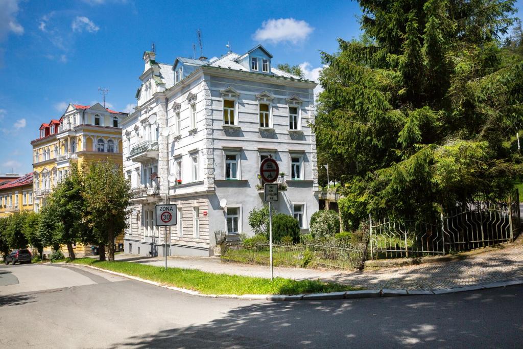 biały budynek na rogu ulicy w obiekcie Apartman Karlovarská w Mariańskich Łaźniach