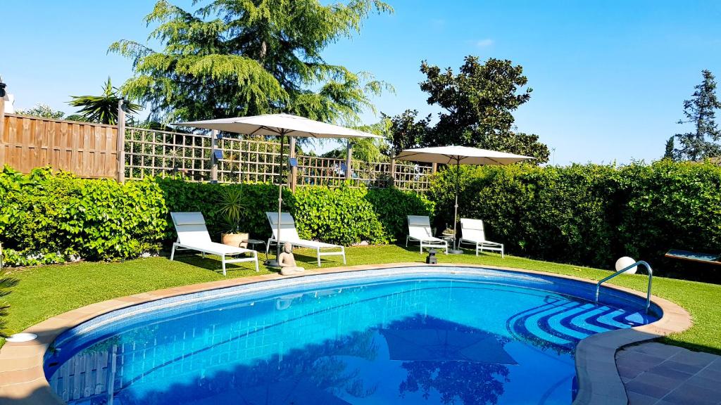 una piscina en un patio con sillas y sombrillas en Stay U-nique Villa Portimar, en Arenys de Mar