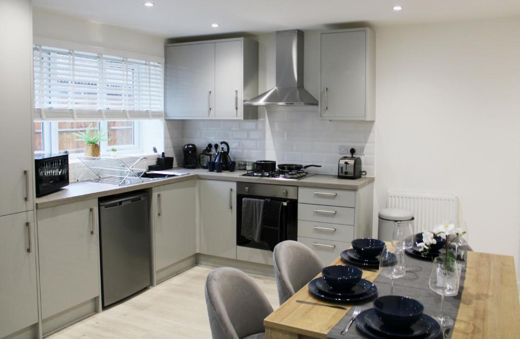 a kitchen with white cabinets and a table with chairs at Didcot - Private Flat with Garden & Parking 07 in Didcot