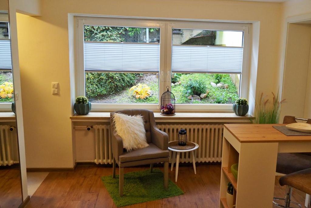 a living room with a chair and two windows at Ferienwohnung Kisslina in Bad Kissingen