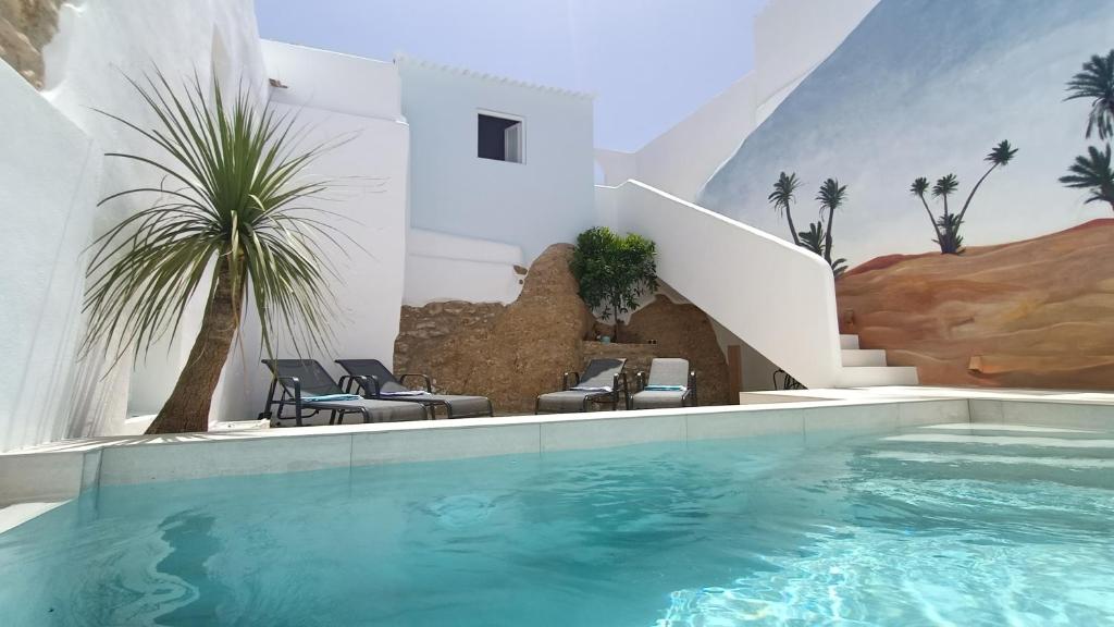 einen Pool in einem weißen Gebäude mit einer Palme in der Unterkunft Buena Vista Ronda Club in Ronda