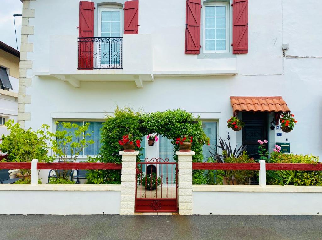 una casa blanca con puertas rojas y una valla roja en Appartement neuf et moderne, en Saint-Palais