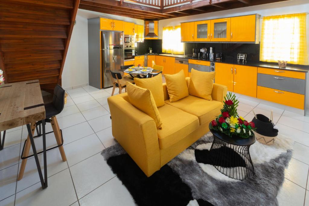 a living room with a yellow couch and a kitchen at VILLA DALHIA in Pointe-Noire