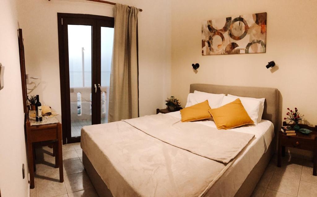 a bedroom with a bed with yellow pillows and a window at Anthoula Apartments in Kokkini Khanion