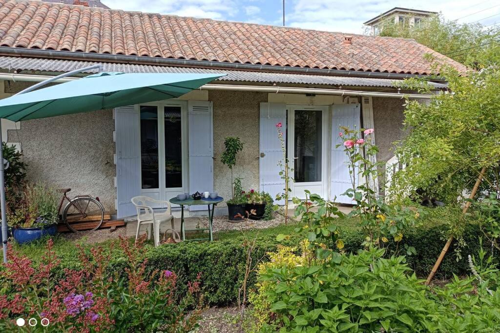 uma pequena casa com uma mesa e um guarda-chuva em Un paradis de verdure en plein centre ville em Périgueux