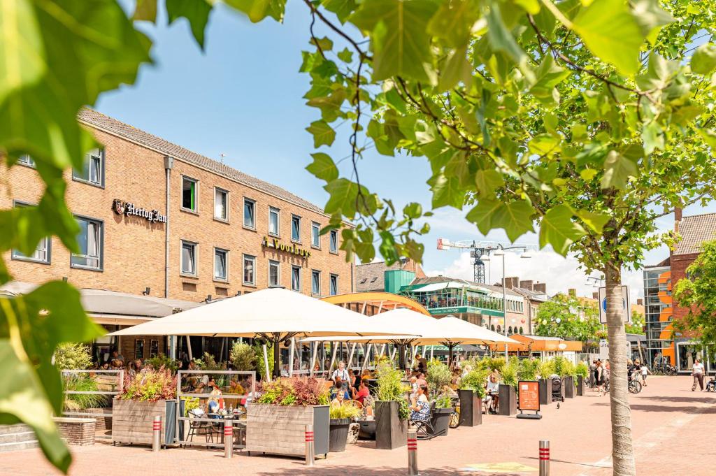 een straat met tafels, stoelen en parasols bij Hotel Restaurant Grandcafé 't Voorhuys in Emmeloord