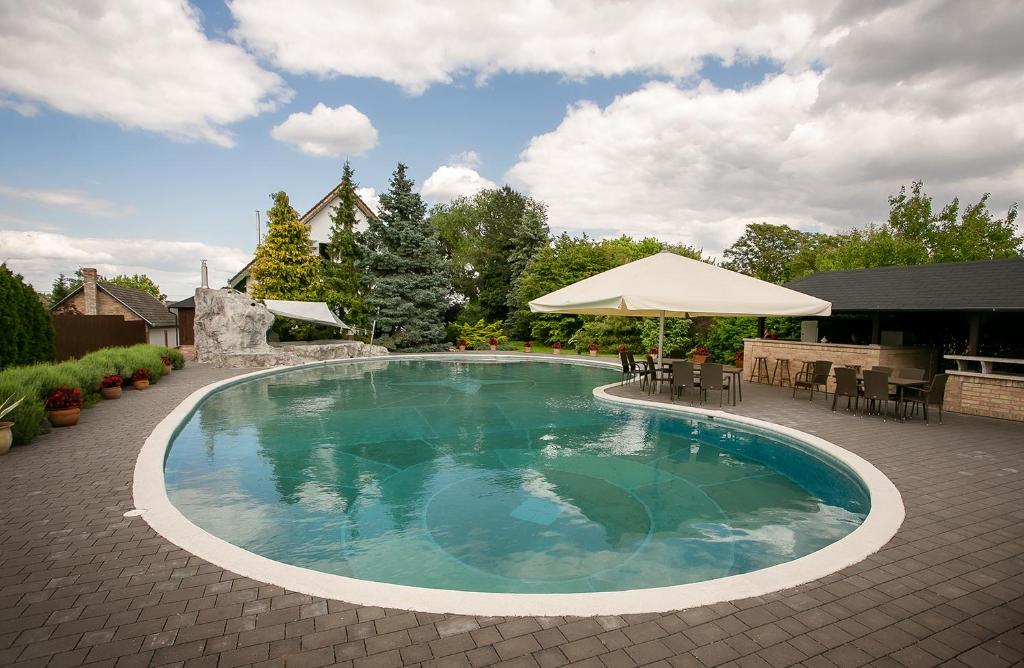 uma piscina com guarda-sol, mesas e cadeiras em Forrás vendégház em Dunaegyháza