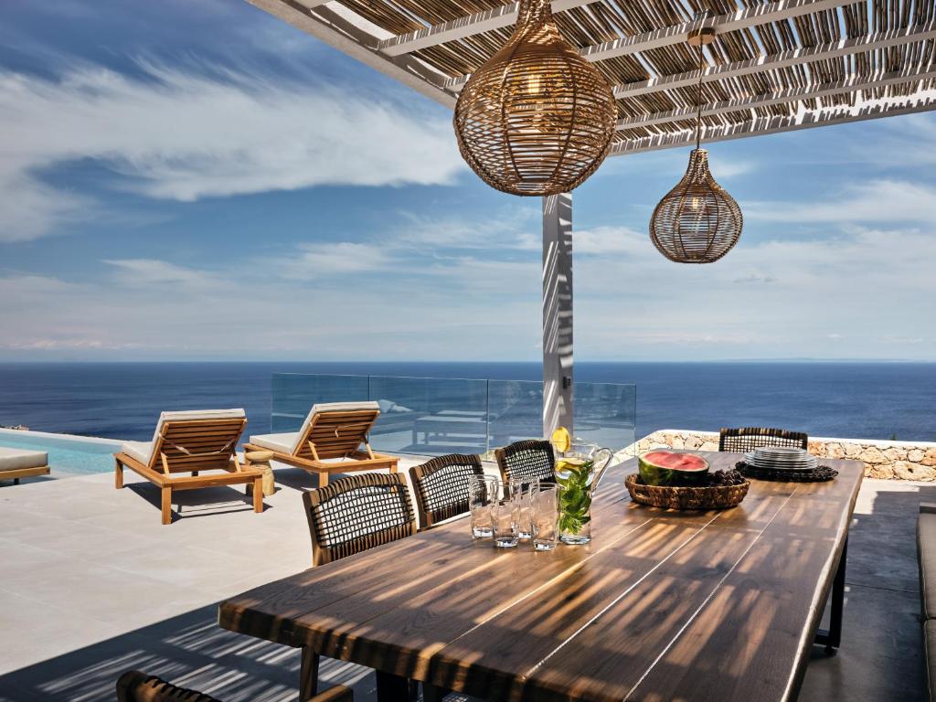 a wooden table with chairs and a view of the ocean at Etheria Luxury Villas & Suites in Agios Nikolaos