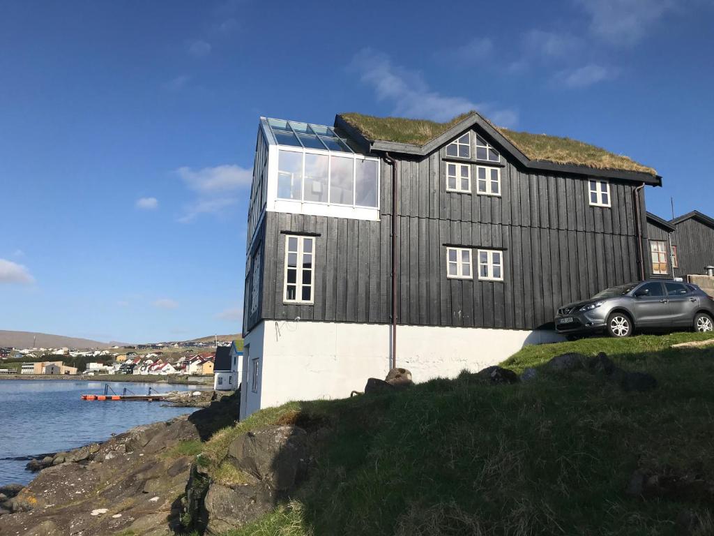 a black house with a car parked in front of it at Tórhús in Miðvágur