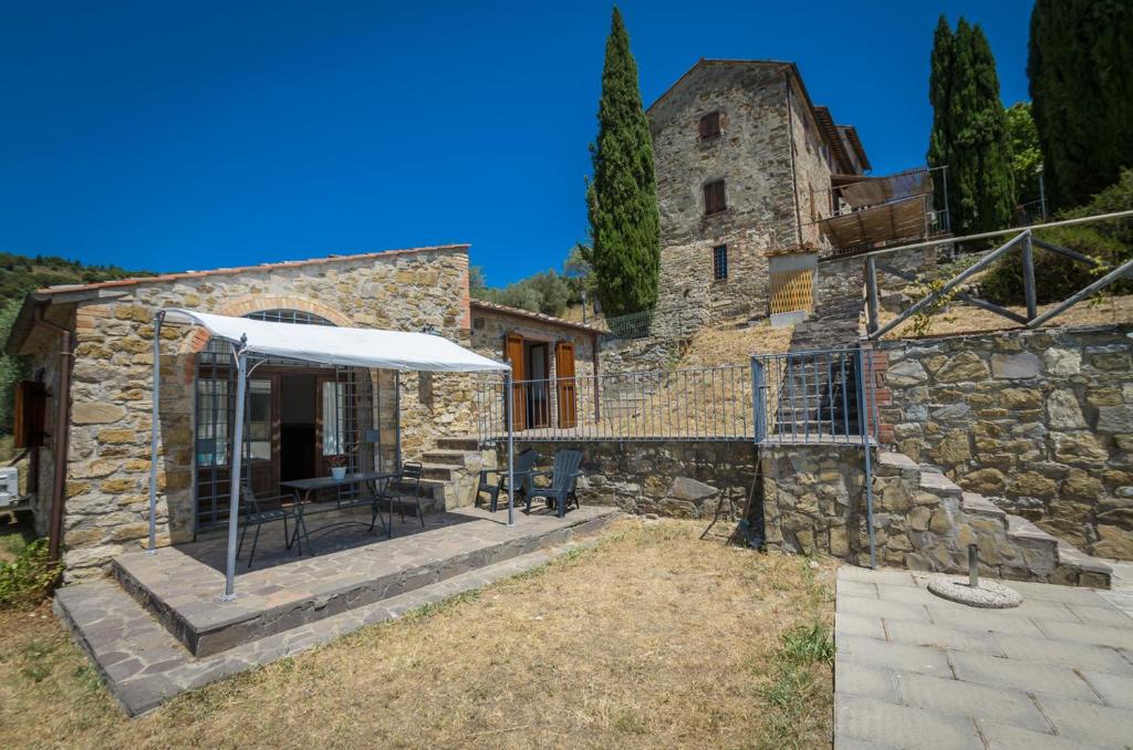 a stone building with a table and an umbrella at PoloTuristicoUmbria Rustico con Piscina Vista Lago in Passignano sul Trasimeno