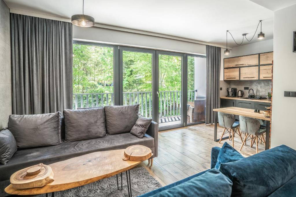 ein Wohnzimmer mit einem Sofa und einem Tisch in der Unterkunft ApartLoft Apartament Szczyrk SAUNA & FITNESS - Skrzyczne Residence in Szczyrk