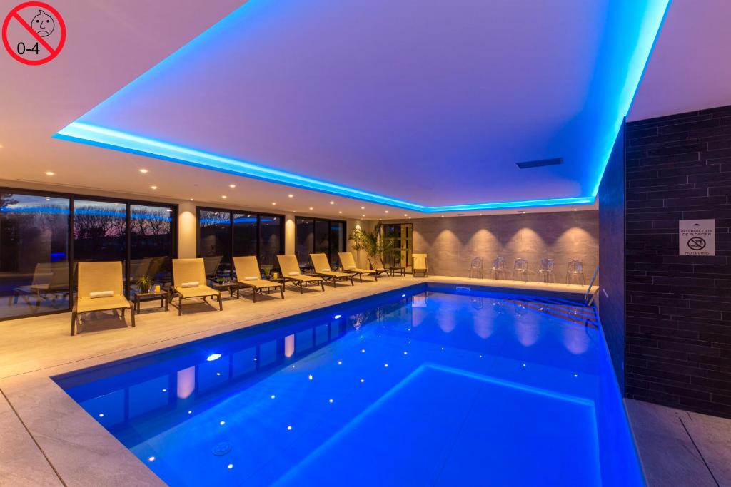 a swimming pool in a hotel with blue lighting at Hôtel L'Escale - Piscine & SPA in Escalles