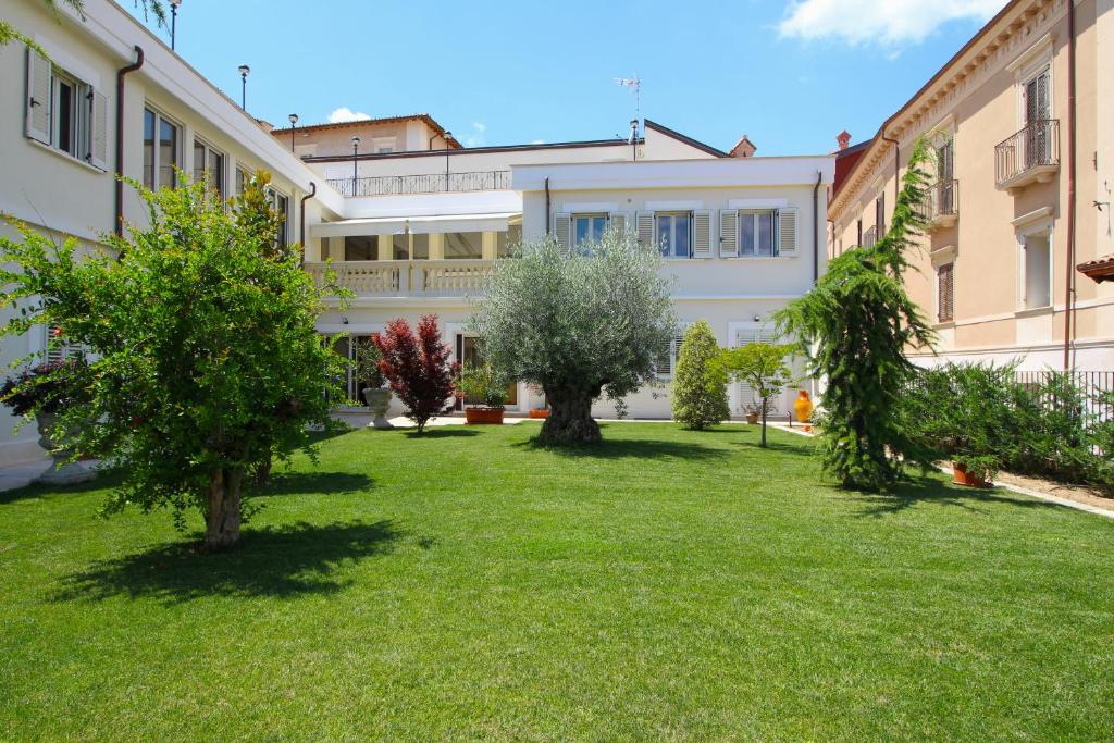 Residenza San Flaviano, Relais di Charme في لاكويلا: ساحة فيها اشجار امام مبنى